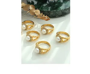 Detailed view of gold pearl rings with zircon halo and twisted bands on elegant marble