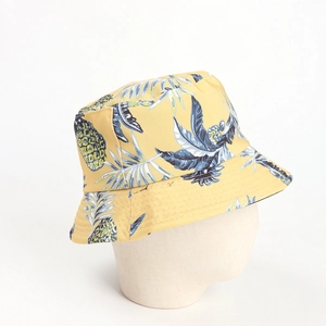 Close-up of a yellow bucket hat featuring tropical pineapple and leaf print patterns