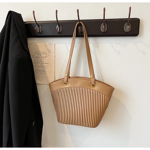 Close-up of khaki straw bag with vertical pleated texture and dual straps on hook