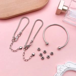 Close-up of DIY silver charm jewelry set with heart pendants and beaded bracelets