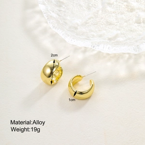 Detailed view of chunky golden C-shaped alloy earrings with internal brand engraving