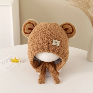 Close-up of baby plush bear ear hat in brown sherpa fleece with leather M tag detail