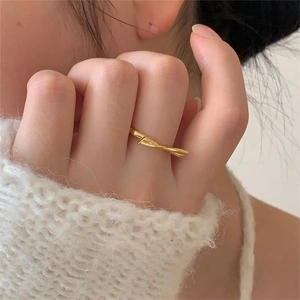Close-up of elegant gold bow ring on finger paired with a soft white knitted sweater