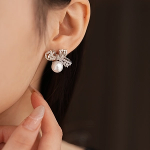 Gros plan sur des boucles d'oreilles nœud avec perle et zircone sur l'oreille
