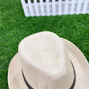 Detail of fine flat-weave texture on light beige straw sun hat with dark brown band