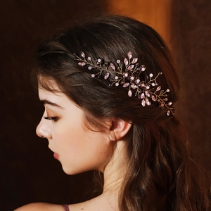 Detalle del peine de novia hecho a mano con cristales rosas y alambre dorado en una modelo