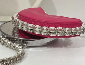 Close-up of bright pink sequin handbag featuring large white rhinestones and a chain strap