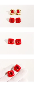 Macro detail of red enamel earrings with gold texture and sparkling square zircons