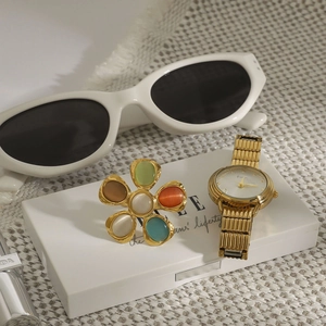 Détail de montre dorée avec accessoire floral à cinq pétales colorés sur boîte