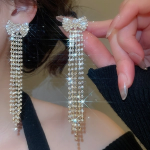 Detailed view of long silver tassel earrings with sparkling zircon bowknot on model
