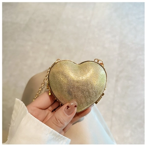 Close-up of a mini heart-shaped gold glitter evening bag with chain hardware