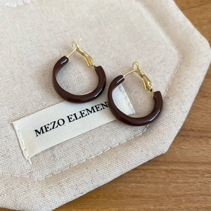 Detailed view of dark brown round hoop earrings on a beige fabric pouch