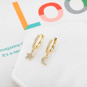Close-up of golden asymmetric hoop earrings with micro-set zircon star and moon charms