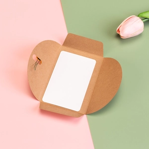Vintage kraft paper heart envelope with white card and pink tulip on pastel background