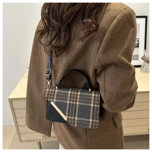 Detail view of vintage plaid wool handbag with leather trim and gold metal accent