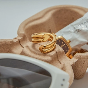 Schicker zweilagiger goldener Titanstahlring mit Herzenden auf einem Designer-Tablett