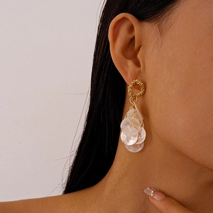 Bohemian gold round earrings with shell fringe worn by a model in a side profile view