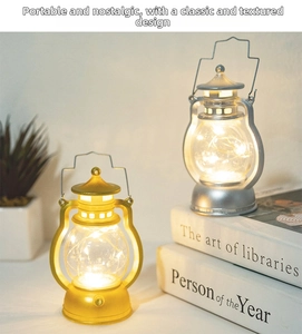 Detail of vintage gold and silver LED lanterns with wire handles on a white book stack