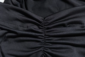 Close-up of ruched detail and fine stitching on a black one-shoulder evening dress