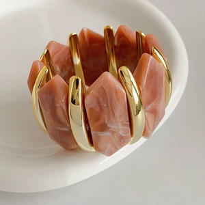Détail du bracelet élastique doré en acrylique avec modules à texture de marbre rose