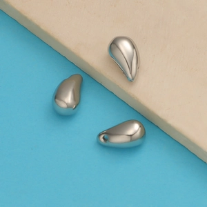 Close-up of three polished silver teardrop pendants and beads for DIY jewelry making