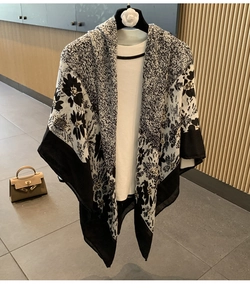 Detail of floral linen blend scarf draped over a white outfit in a boutique setting
