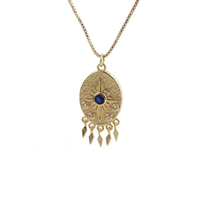 Gold evil eye necklace with blue zircon and starburst pendant on a white background