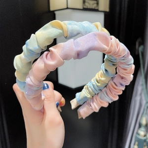 Close-up of pastel tie-dye pleated fabric headbands with braided metal chain texture