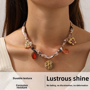 Detail of bohemian floral ribbon necklace with sunflower and butterfly pendants on neck