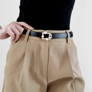 Detail of thin black leather belt with a gold square buckle inlaid with sparkling rhinestones
