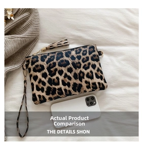 Detail view of leopard print clutch with zipper closure, tassel charm, and wrist strap