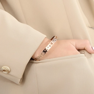 Detailed view of cutout star cuff bracelet in 18K gold plating on a model's wrist