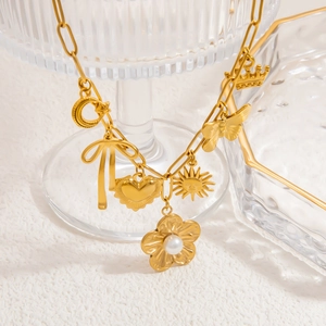 Détail du collier plaqué or 18 carats avec breloques couronne, papillon et perle sur la chaîne
