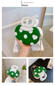 Detail view of green mushroom handbag with white polka dots and gold chain strap