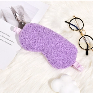 Detail of purple teddy plush sleep mask with silk texture elastic strap on soft white rug