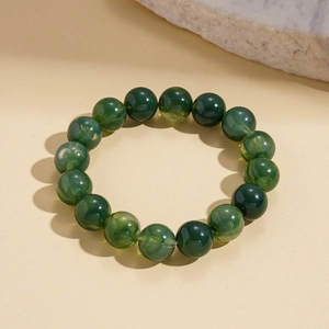Detailed shot of green acrylic beads with swirl patterns on a textured stone surface