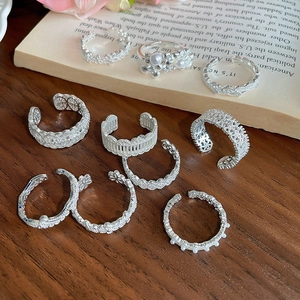 Detail of vintage silver lace rings with floral and pearl accents on book pages