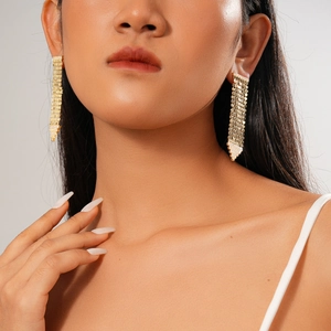 Gros plan de boucles d'oreilles à pompons plaquées or 18 carats portées par un mannequin