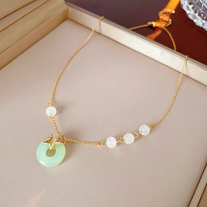 Close-up of gold-plated ginkgo leaf necklace with green Ping An Kou glass pendant
