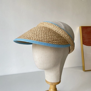Détail d'une visière en paille de raphia avec bordure en tissu bleu clair sur mannequin