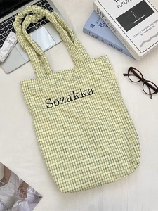 Yellow checkered canvas tote bag with black letter print and wide handles in top view