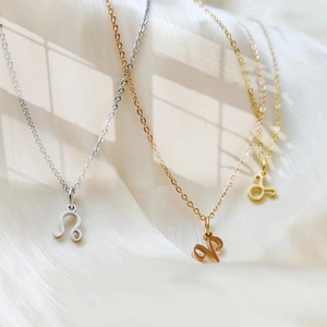 Macro shot of minimalist stainless steel zodiac necklaces in gold silver and rose gold finishes