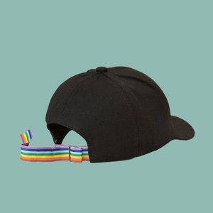 Close-up of black cotton baseball cap showing adjustable rainbow webbing strap on back