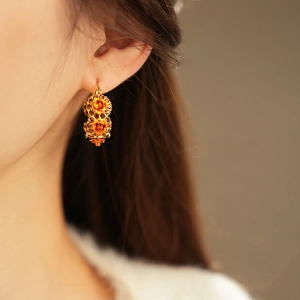 Close-up of vintage gold floral earrings with orange roses and amber rhinestones