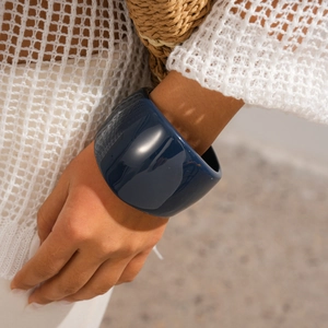Close-up of a wide navy blue resin bangle with a polished mirror finish on a model
