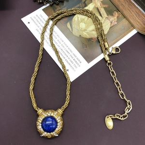 Macro shot of vintage gold chain necklace with round lapis blue gemstone and rhinestones