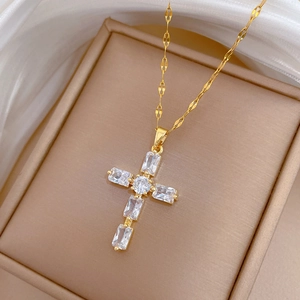 Gros plan du pendentif croix dorée serti de zircons dans une boîte à bijoux