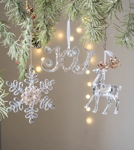 Sparkling transparent acrylic Christmas ornaments with JOY text and reindeer on pine branch