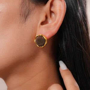 Detailed view of vintage gold-trimmed round earring with dark brown flocking texture