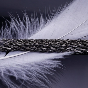 Close-up of black punk twist chain necklace with artistic white feather decoration